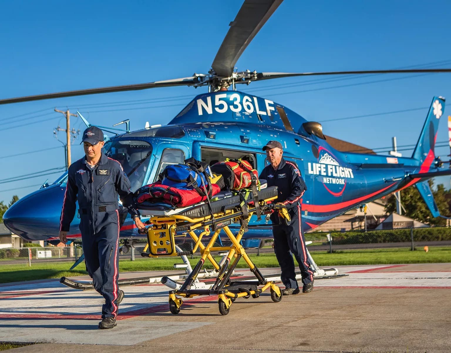 Air medical crew transporting a patient on a stretcher beside a life-flight helicopter